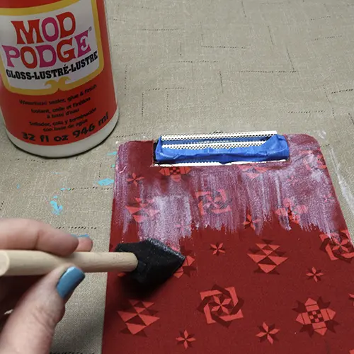 glue the fabric to the clipboard with Mod Podge and then add a coat on top of the fabric to seal.