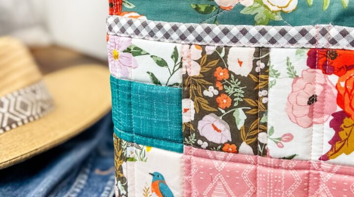 The patchwork pockets version of the Maggie poppins tote made by Remi Vail Studio sitting on a wooden bench with a jean jacket and hat sitting next to it. The photo is of the exterior pocket detail.