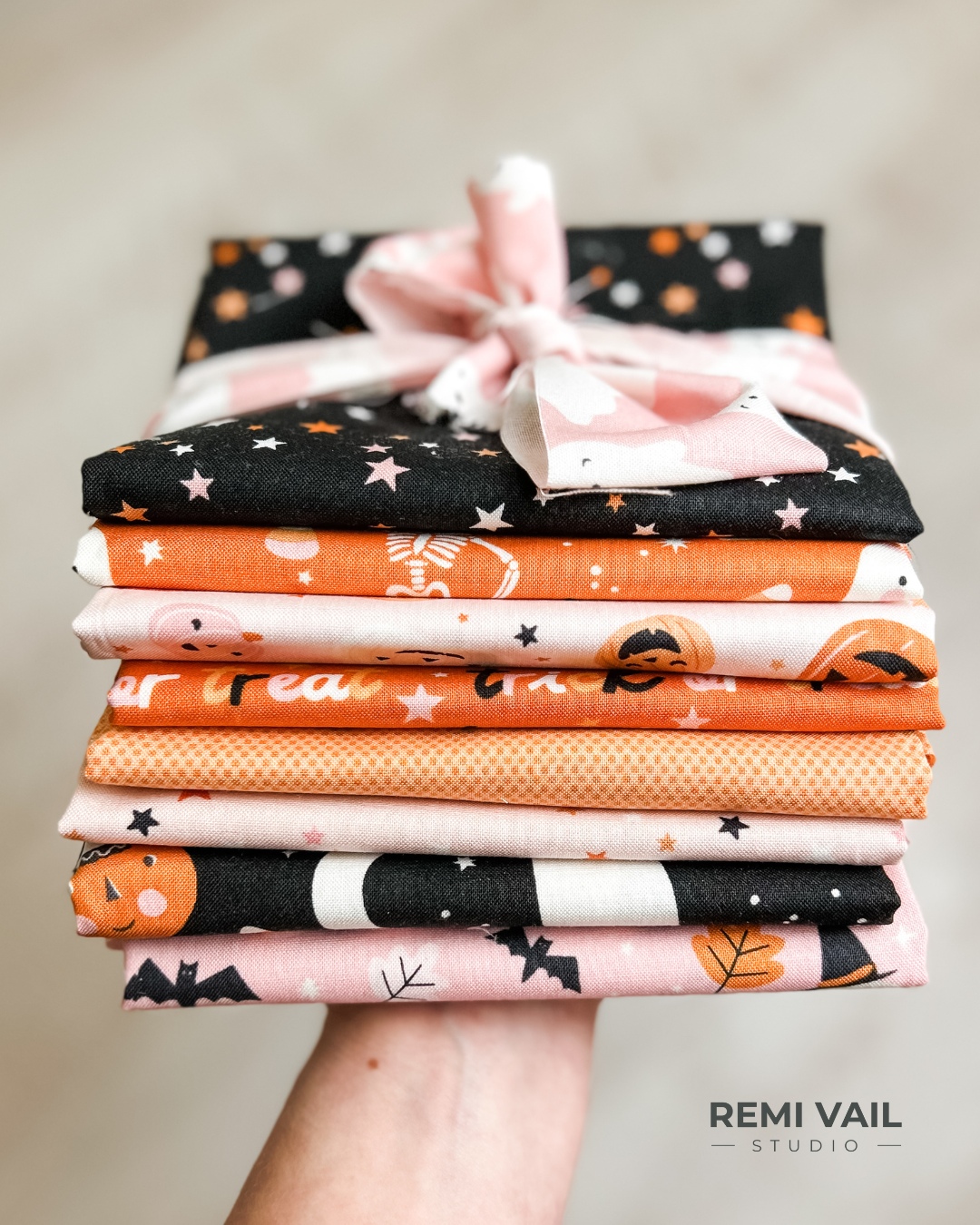 Stack of fabric including an assortment of fabrics from the Hey Pumpkin fabric collection by Riley Blake Designs. Tamara Darragh is holding the fabric bundle. Photographed by Tamara Darragh for Remi Vail Studio.