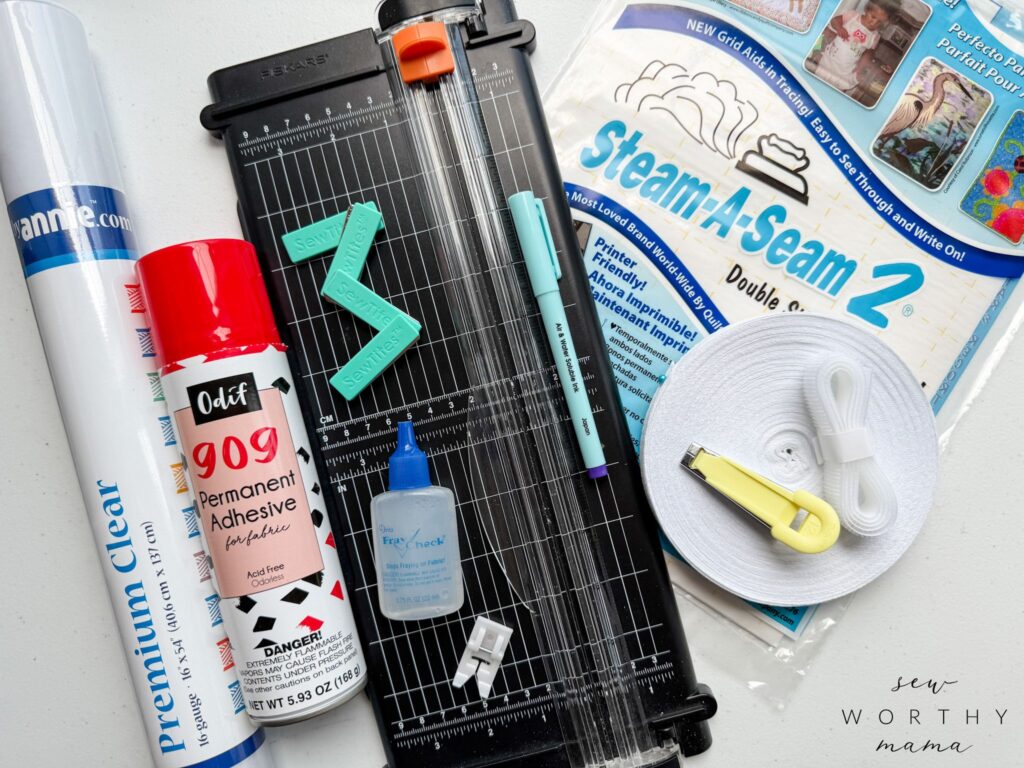 Supplies needed for the Pockets Full of Dreams pattern. A roll of Premium clear vinyl from By Annie's. A can of Odif 909 Permanent adhesive spray for fabric. A Fiskars paper trimmer. 4 Sew Tites magnetic pins. A removable marking pen. Fray Check. A teflon non-stick presser foot. A package of Stema-A-Seam 2 sheets. A roll of twill tape. A roll of Velcro. A 12 mm bias tape maker.