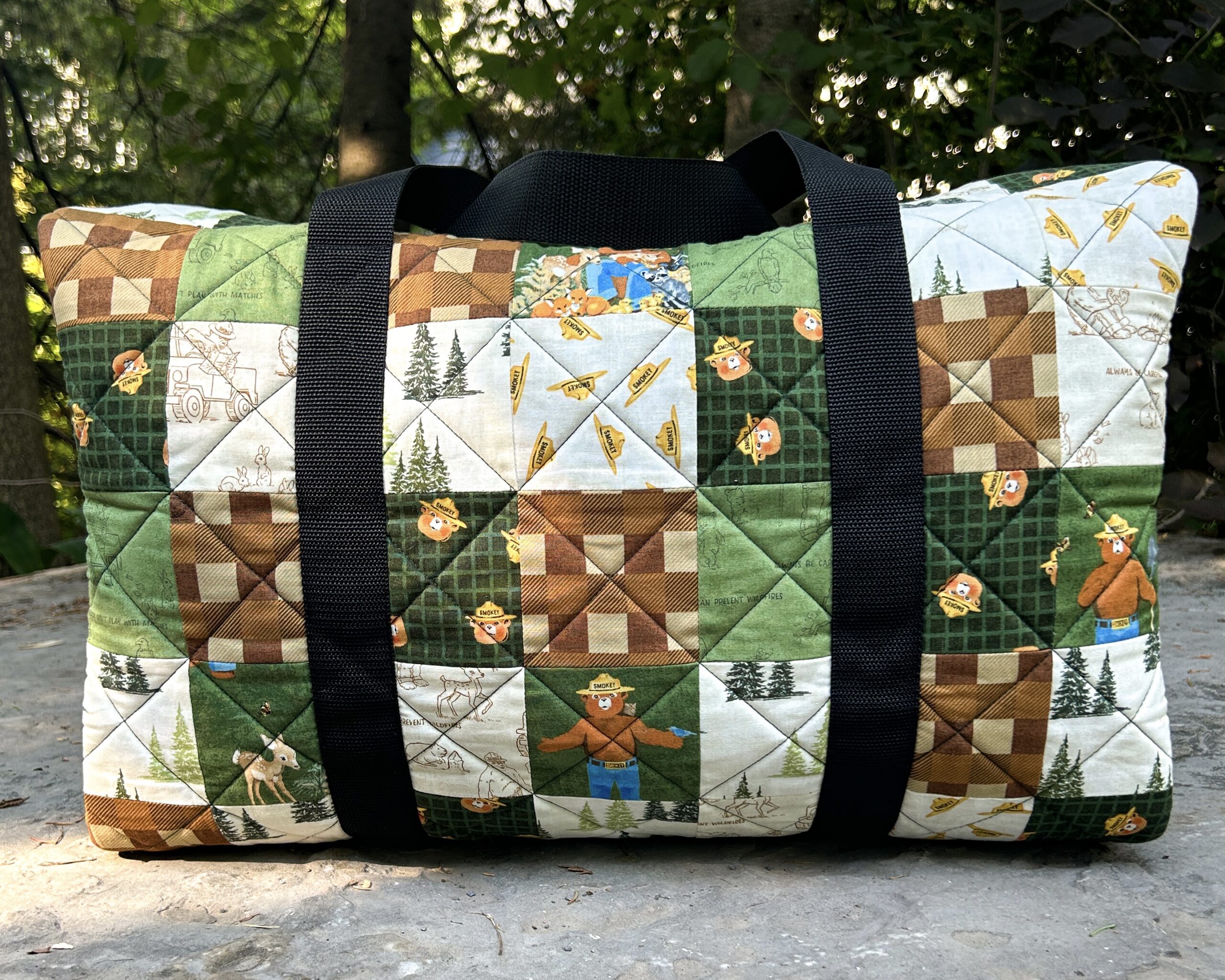 Side view of the completed patchwork duffle bag, sitting on a rock.