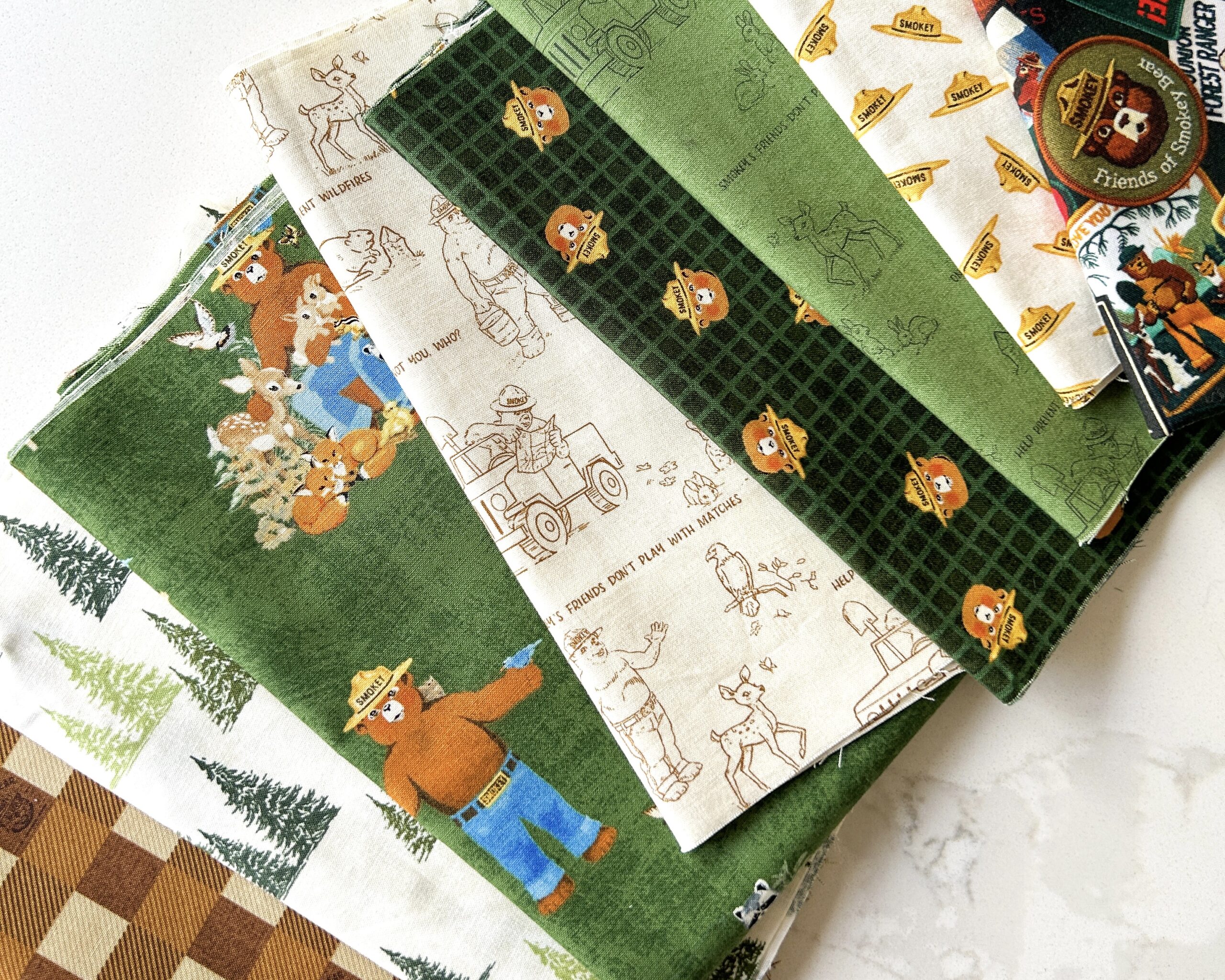Eight various fabric prints are arranged on a white marble countertop.