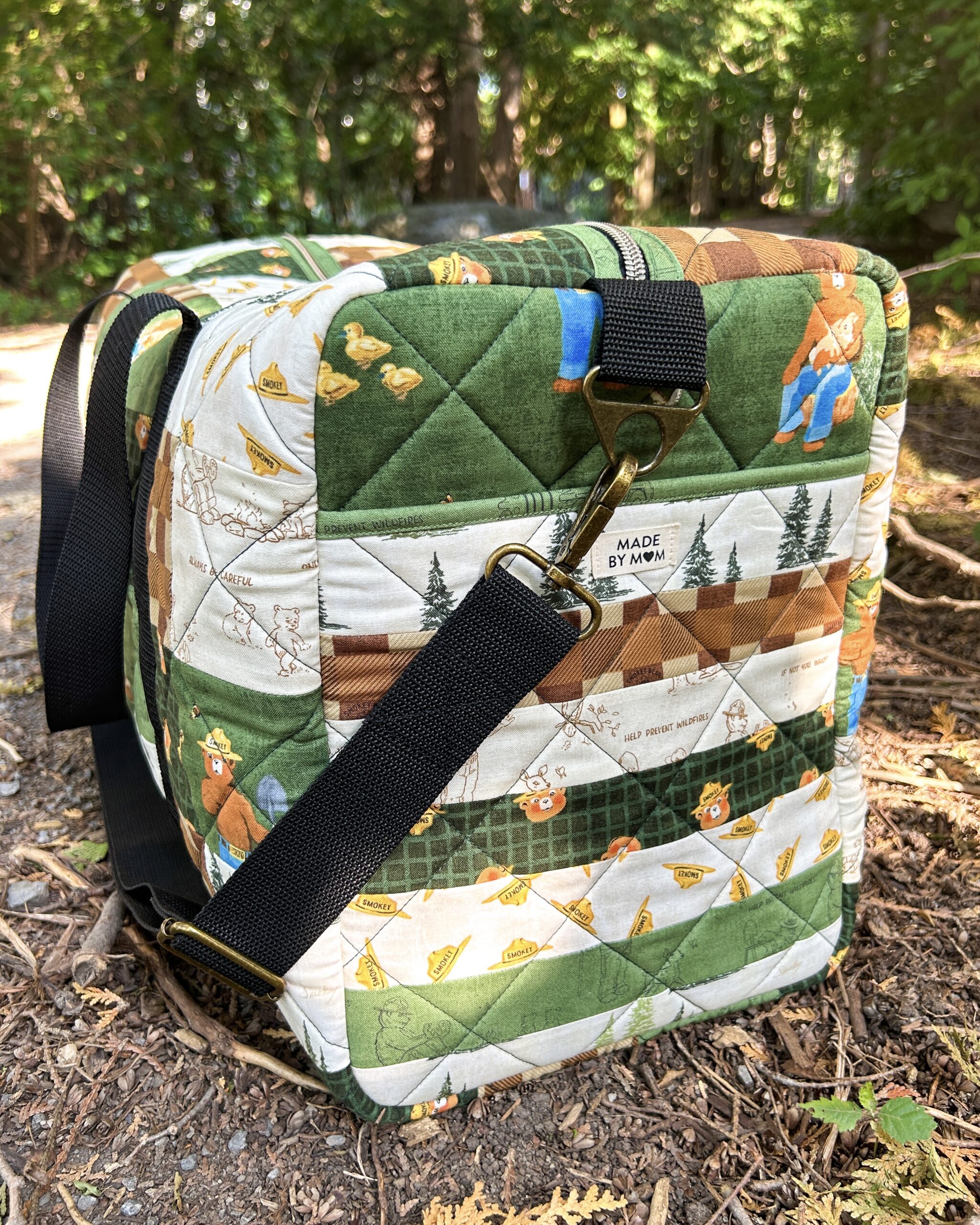 Side panel of the quilted duffle bag featuring horizontal 1.75-inch strips of various green, cream, and brown fabrics.