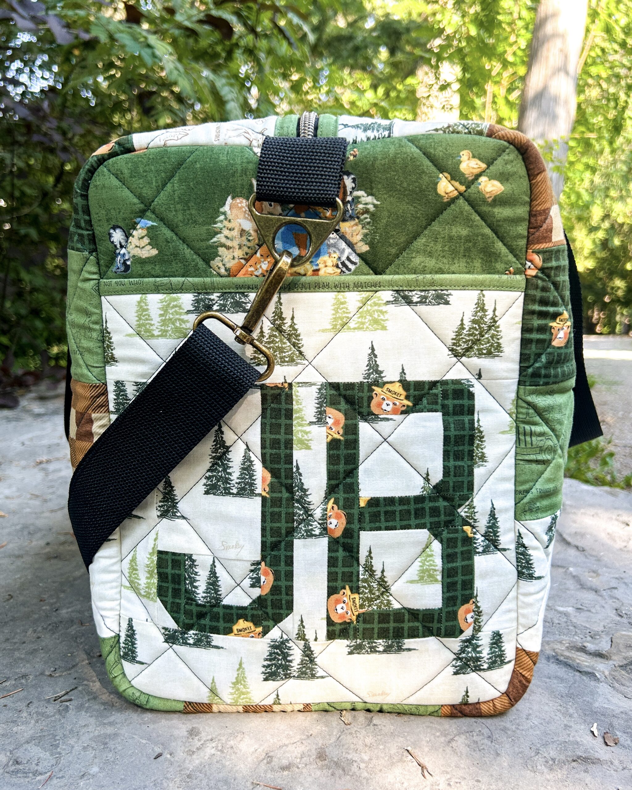 Side panel of the quilted duffle bag featuring a foundation paper pieced block with the initials "JB".