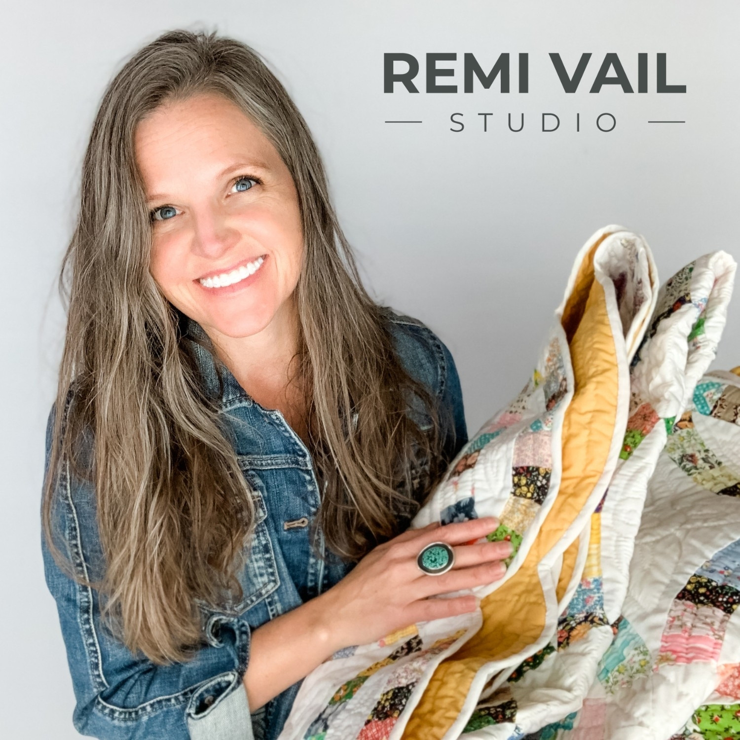 Tamara Darragh of Remi Vail Studio smiling while holding a vintage quilt that belonged to her grandparents, photographed against a light background.