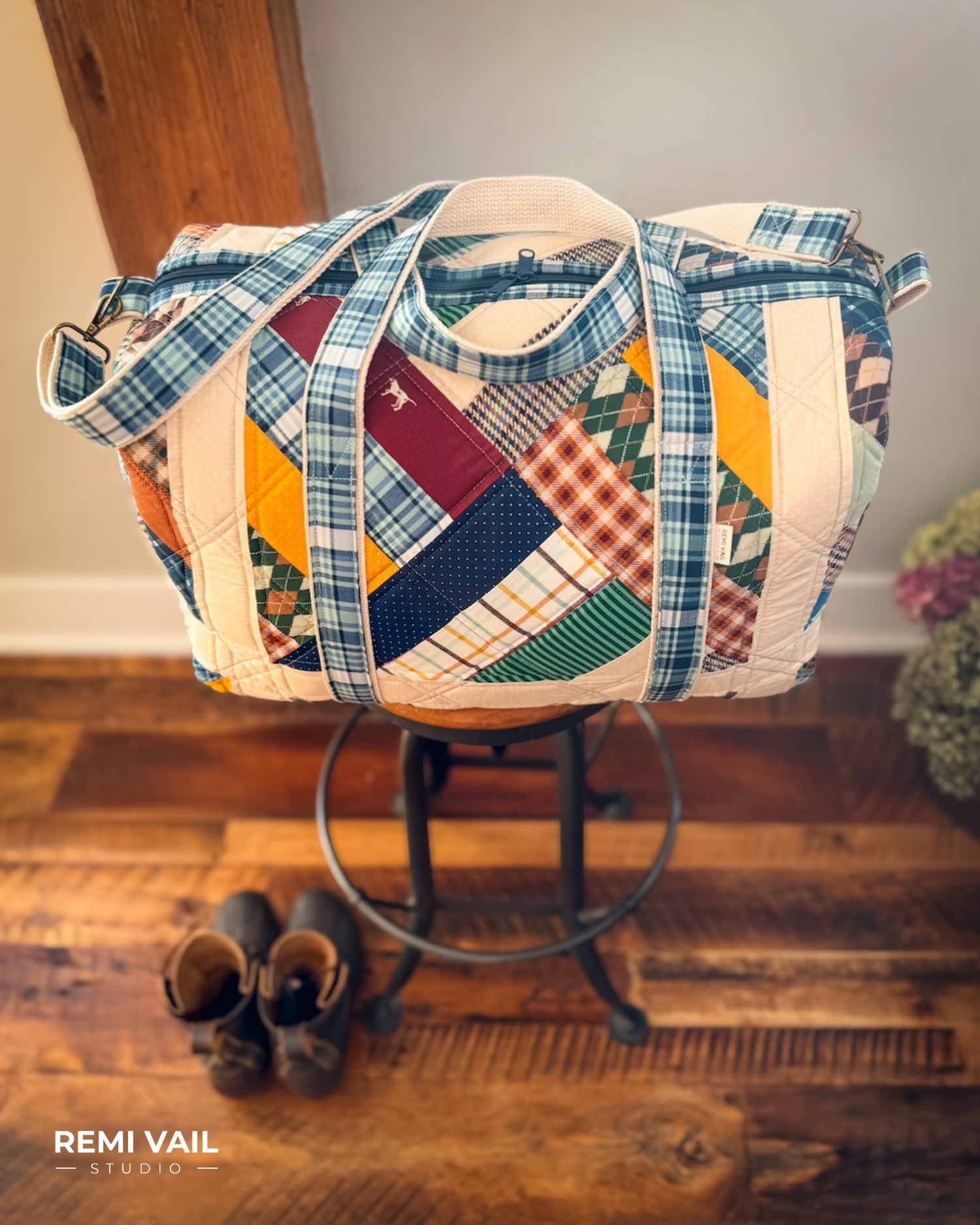 Patchwork Duffle made from Plaid Venture Club Fabric Collection. Made by Tamara Darragh of Remi Vail Studio. Duffle sitting on stool.