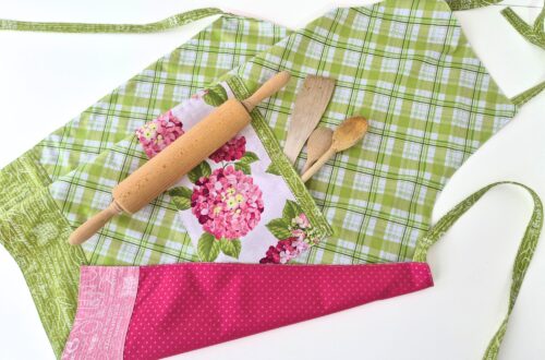 Finished reversible apron with hydrangea pocket and baking tools.